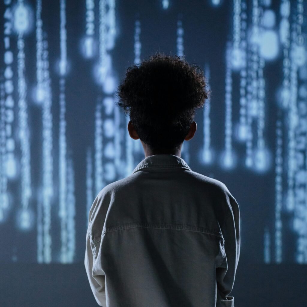 pexels photo 9783350 9783350 Back view of a child sitting and facing a digital display, evoking technological themes.